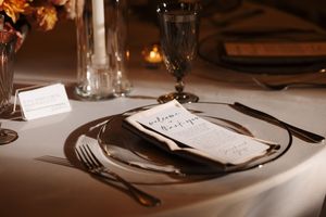 A row of elegant place settings at a formal dining table with white plates and silverware arranged neatly.