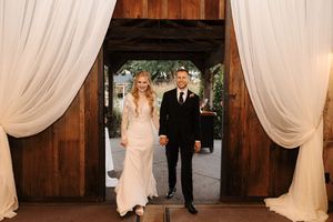 A wedding ceremony setup in a rustic barn venue with white fabric draping and elegant decor details.
