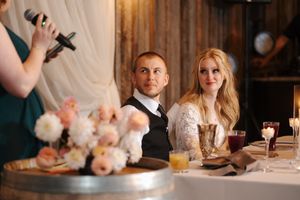 Wedding guests seated at an elegant reception table with white floral centerpieces and glowing candlelight.