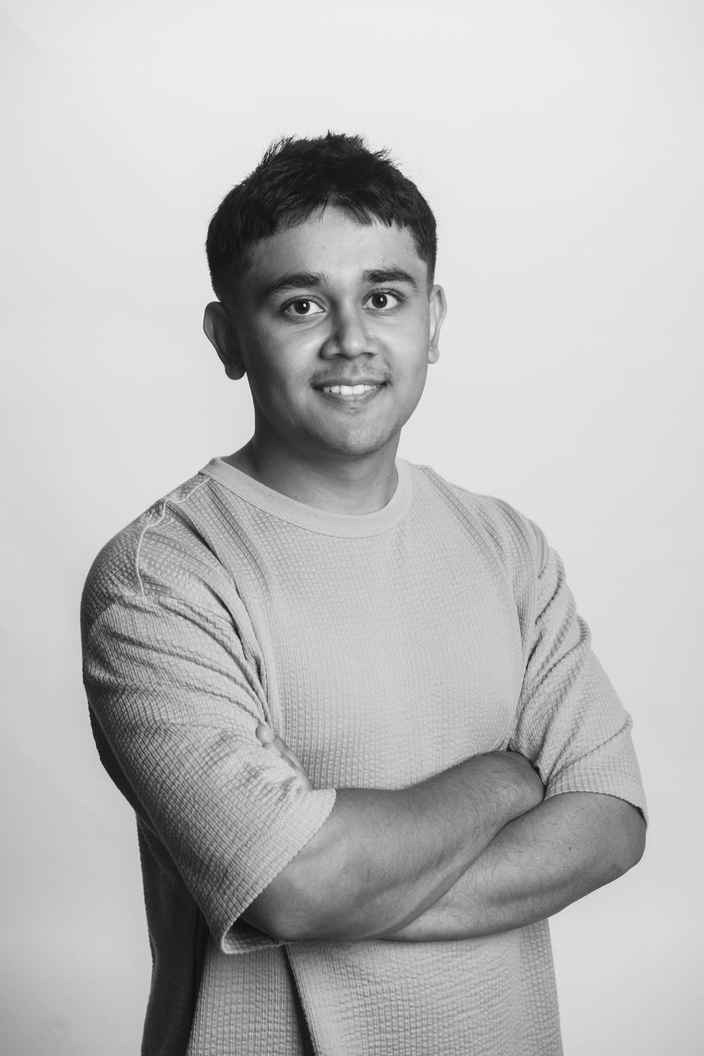 Portrait of a young man with arms crossed wearing textured t-shirt in black and white portrait.