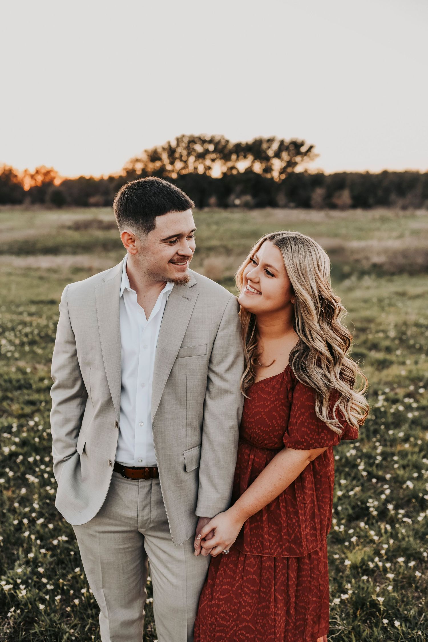 Engagement photos with tiny white flowers in a field at Murrell Park.