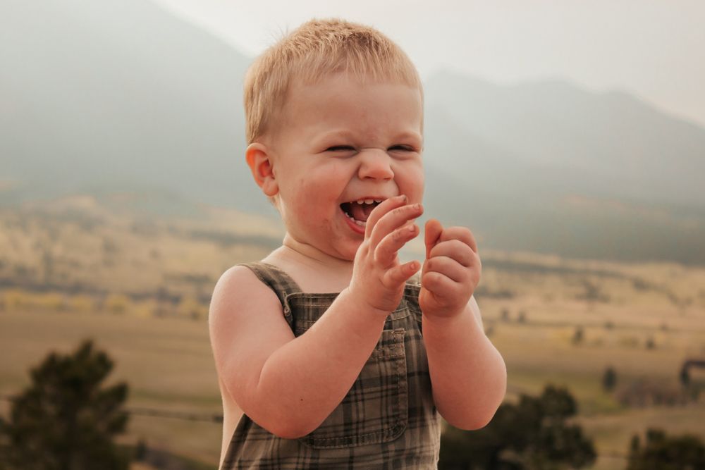 Toddler in denim overalls sitting on a path during golden hour | What to Wear for Family Photos