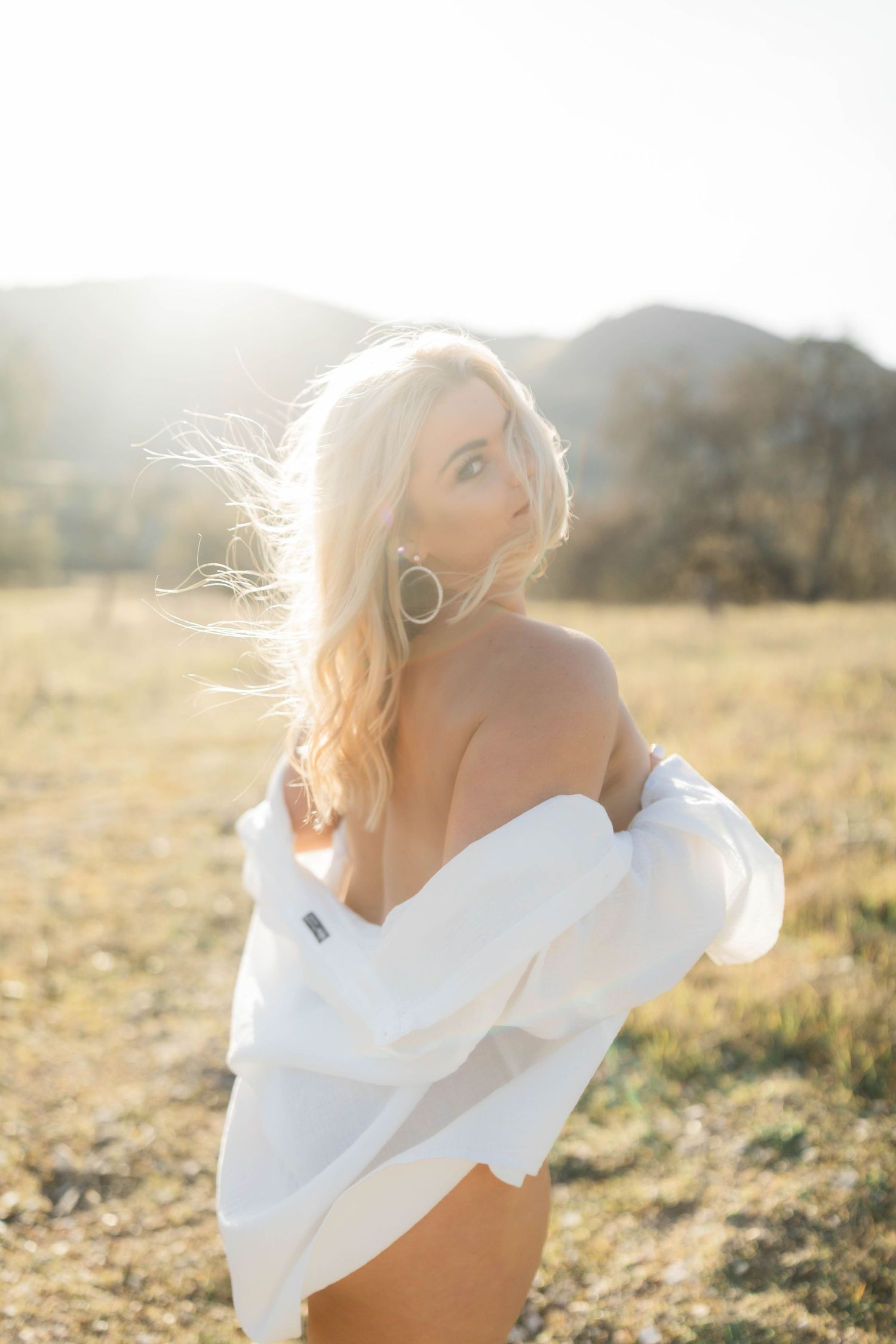 Ethereal portrait of someone in a white shirt against golden sunlit field during magic hour.
