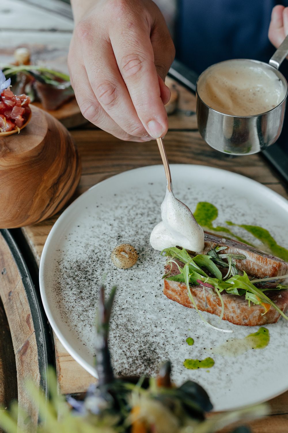 Chef servant un plat gastronomique avec sauce à la crème sur une assiette blanche dans un restaurant gastronomique. Photographe var cuisine