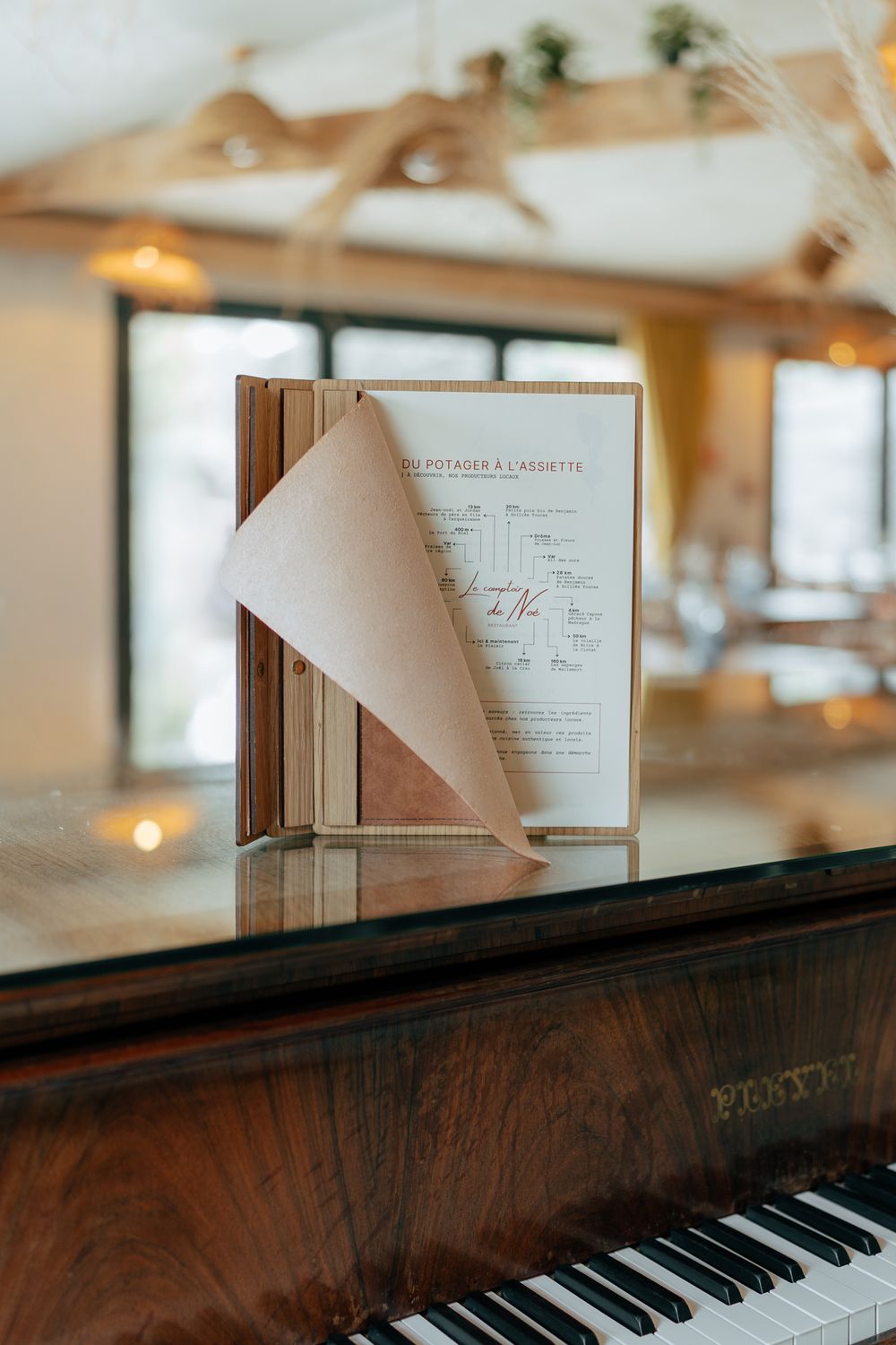 A restaurant menu displayed on a grand piano in an elegant dining room with warm lighting.