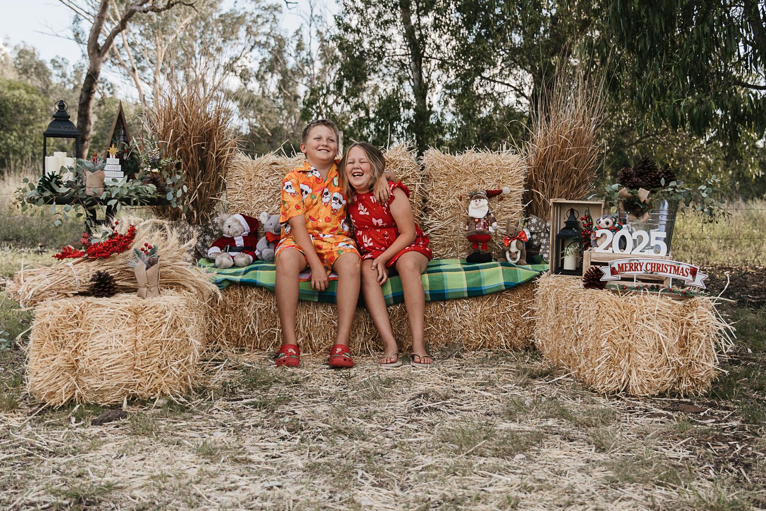 family sitting on hay bales at country, rustic christmas mini photo shoot