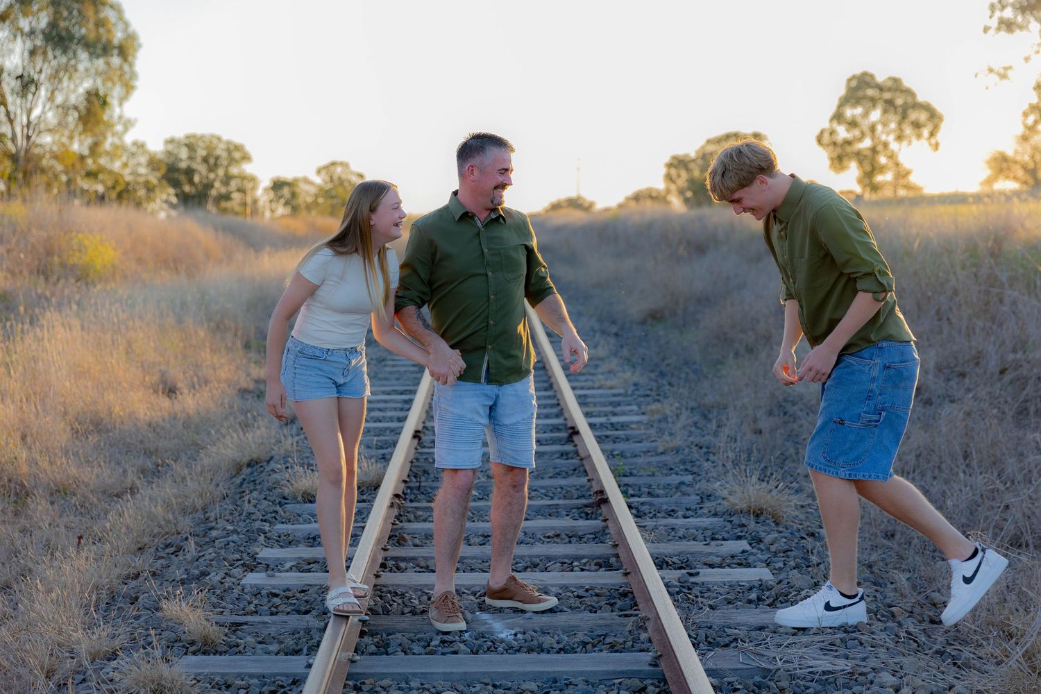 Father and children standing on railway line at sunset during a father's day mini photo shoot