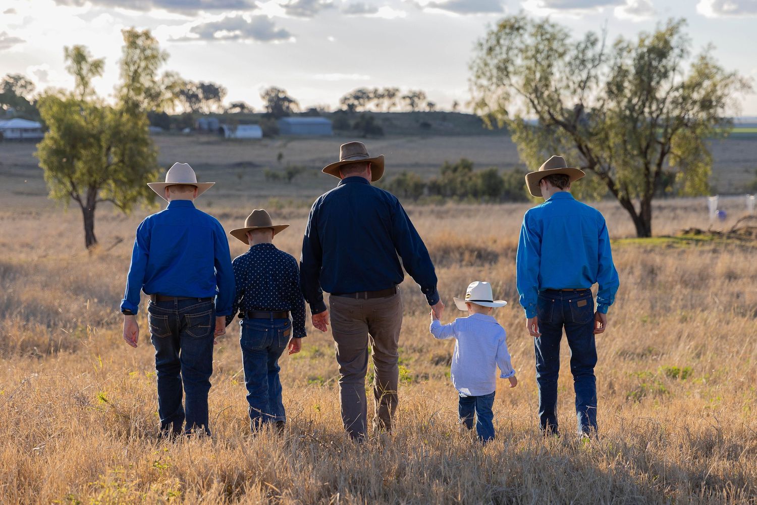 father and sons walking away in paddock for father's day mini photo shoot