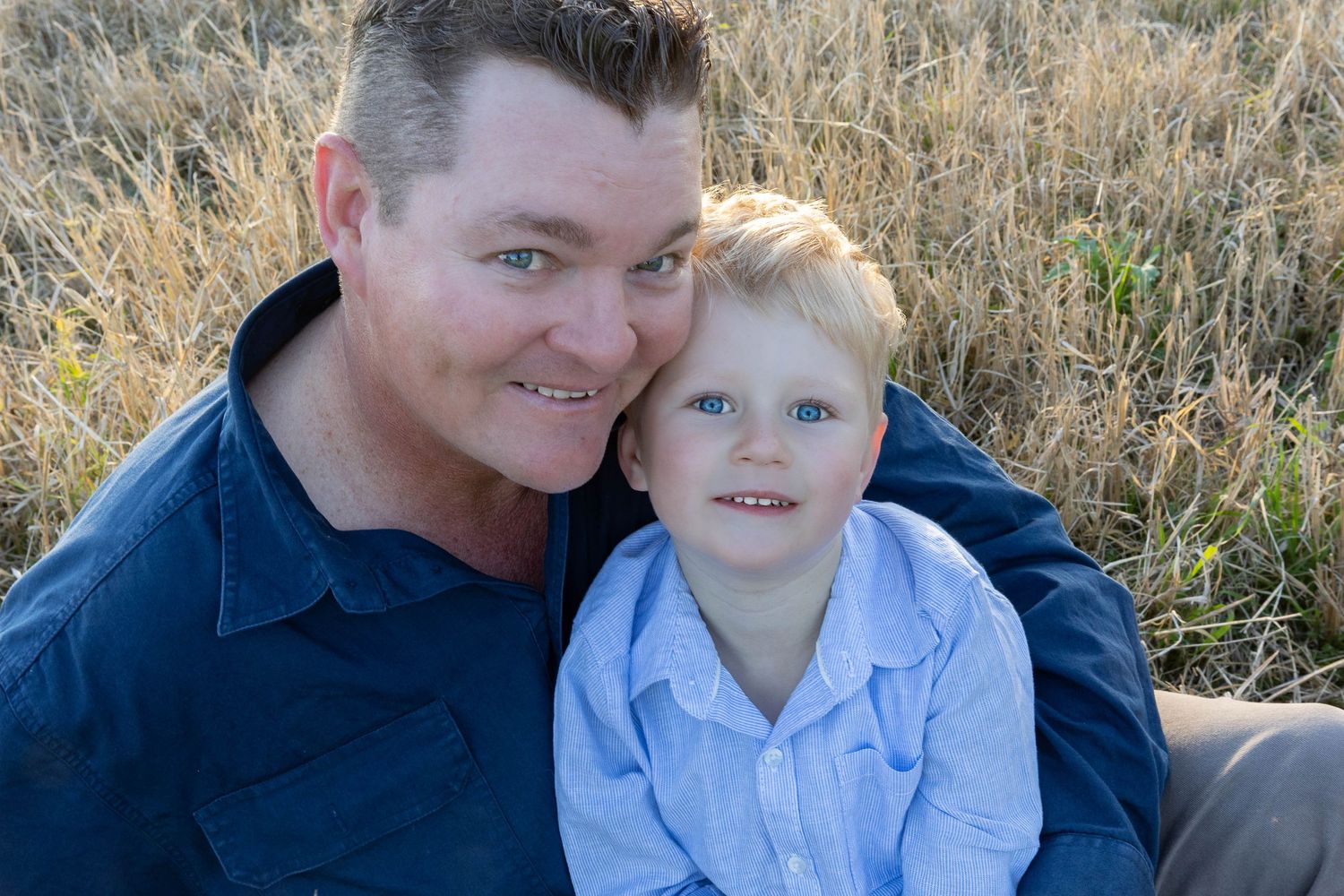 father and son sitting in paddock for father's day mini photo shoot