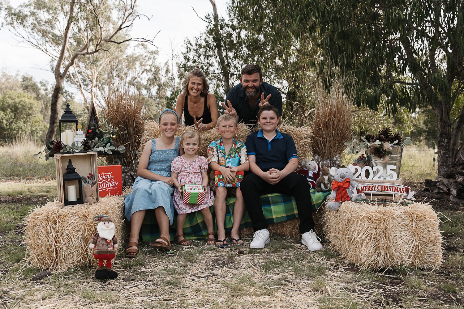 family sitting on hay bales at country, rustic christmas mini photo shoot