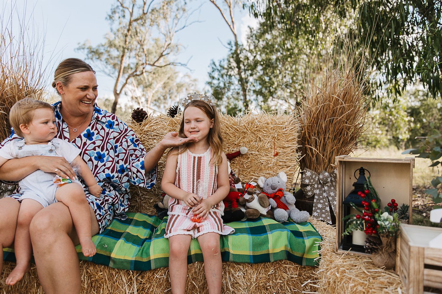 family sitting on hay bales at country, rustic christmas mini photo shoot