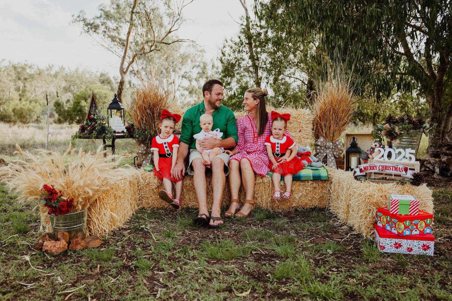 family sitting on hay bales at country, rustic christmas mini photo shoot