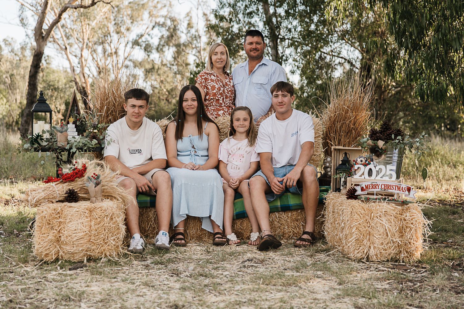 family sitting on hay bales at country, rustic christmas mini photo shoot