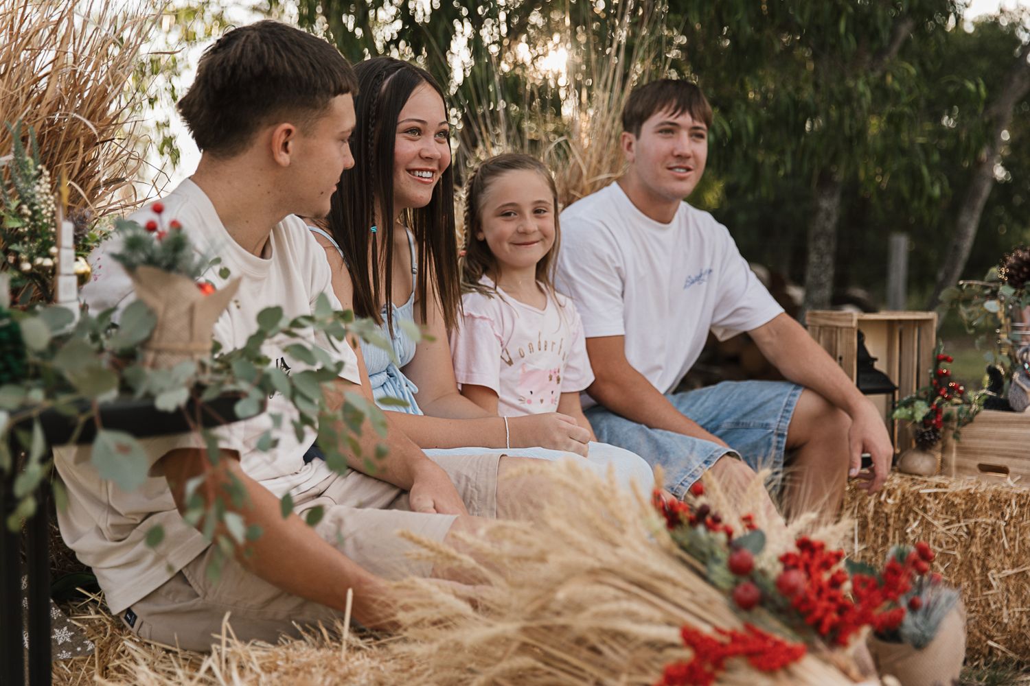 family sitting on hay bales at country, rustic christmas mini photo shoot