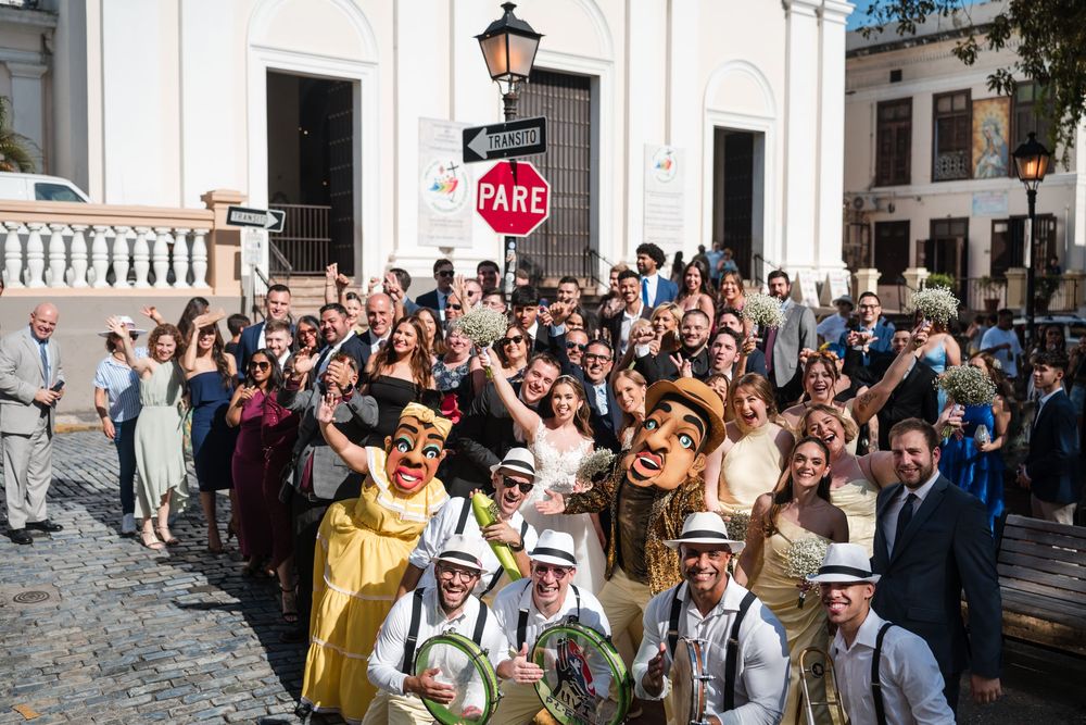 Large group celebrating with bride and groom during plena parade outside in Old San Juan