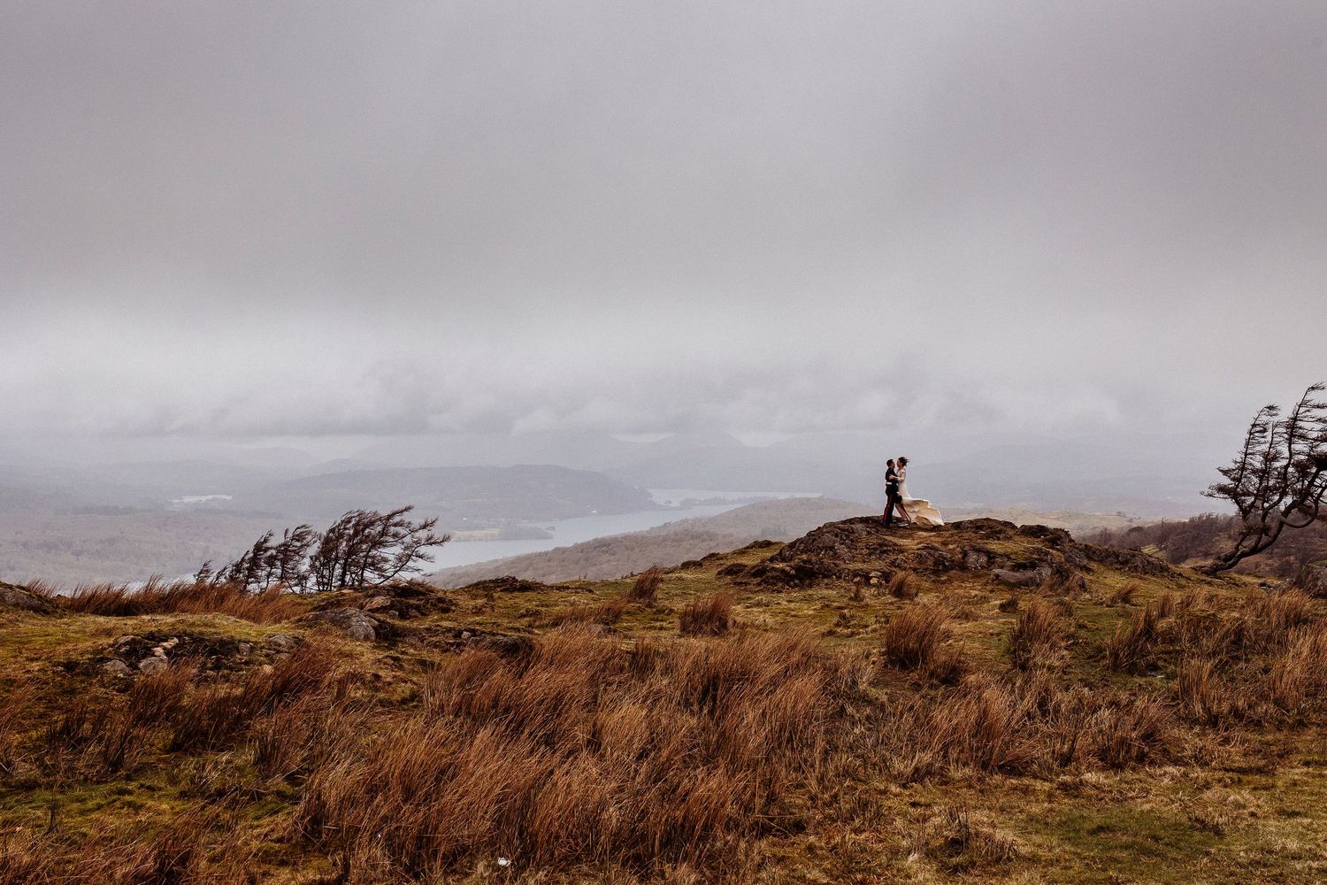 Bride and groom stand against a very moody backdrop with some gorgeous light.