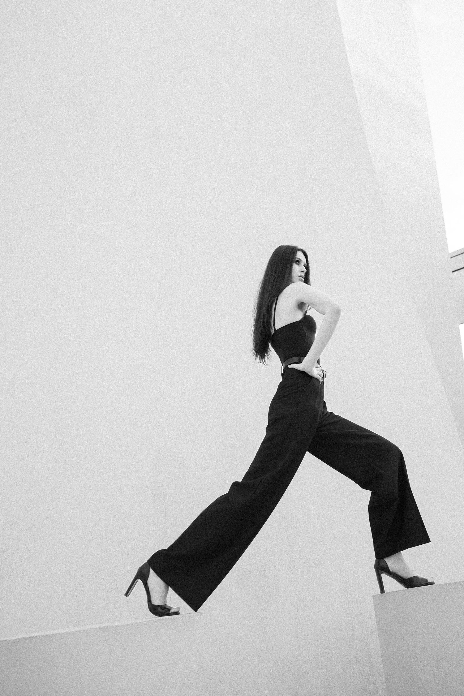 A black and white artistic photo sequence showing a figure in dark clothing leaping and floating against a white background.