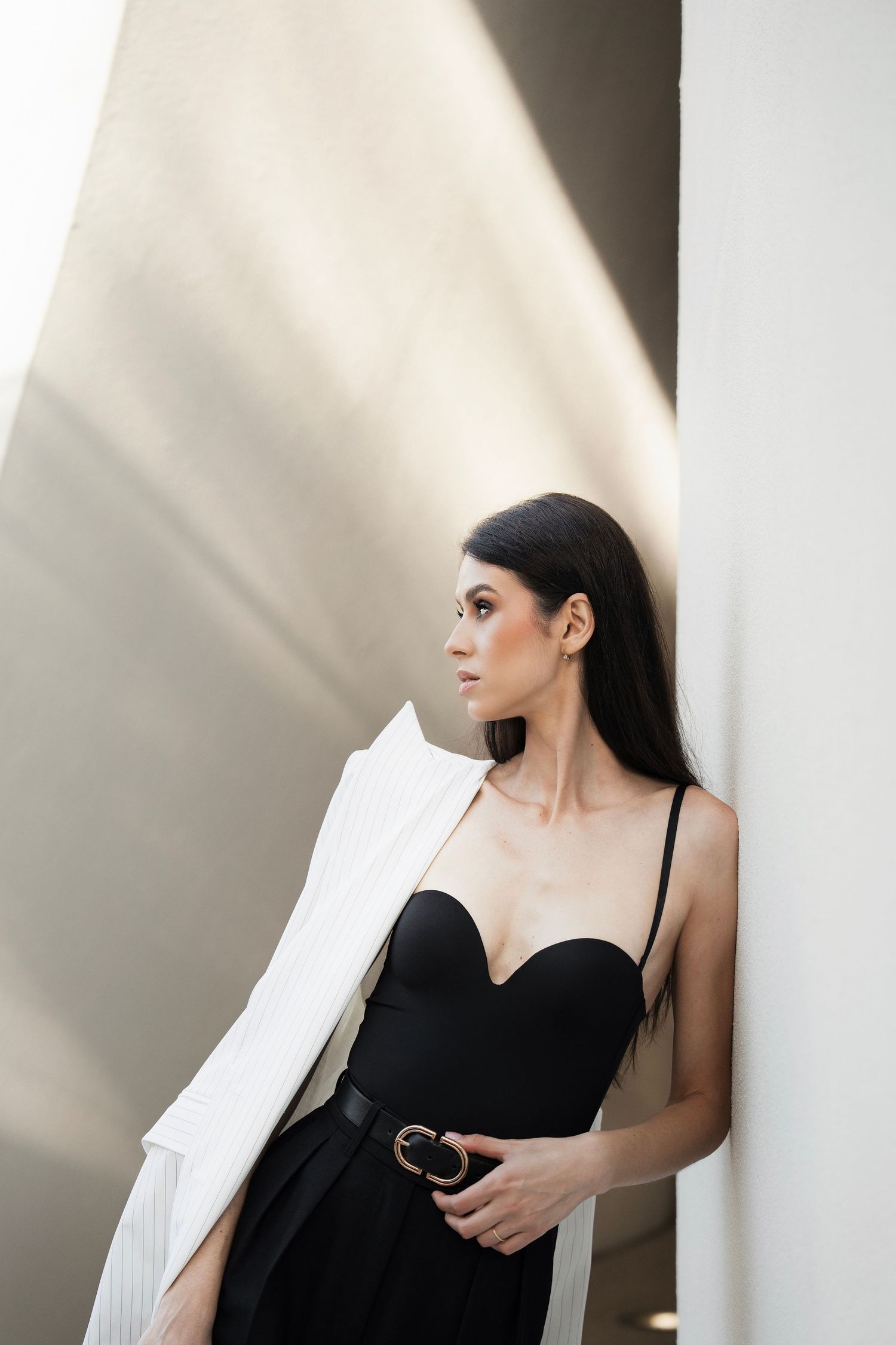 A series of dramatic black and white portraits showing a woman in a black dress against a white wall with shadows.