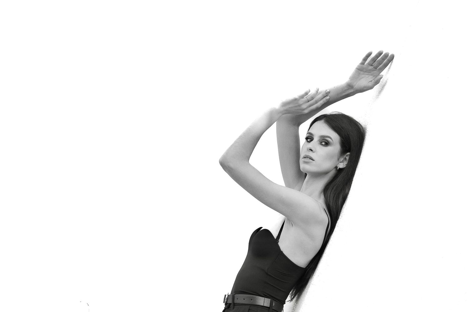 A group of dancers in black leotards perform graceful ballet poses against a white background.