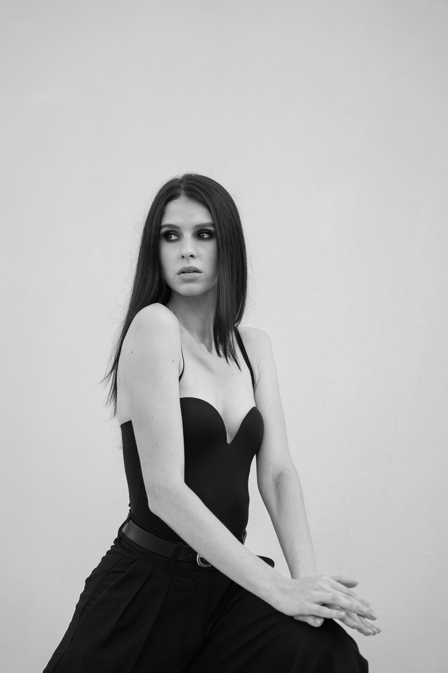 A dramatic black and white fashion portrait series showing poses in a black sleeveless dress against white backdrop.