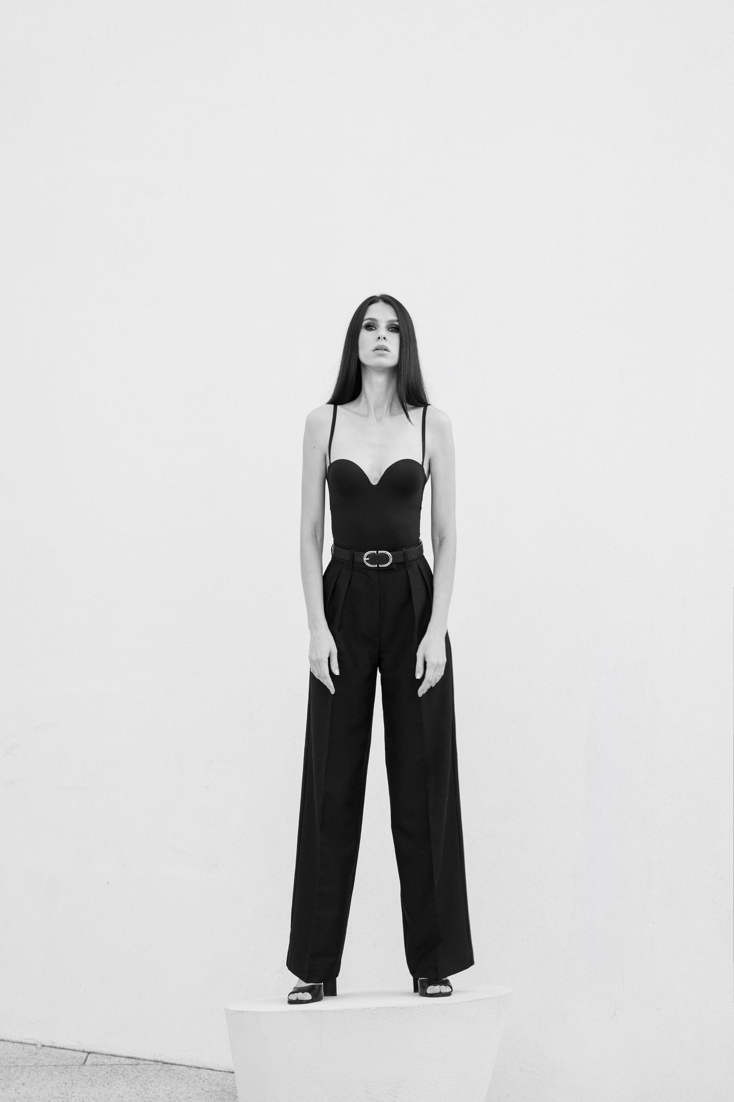 Minimalist fashion photography featuring wide-leg black pants and white jacket ensemble.