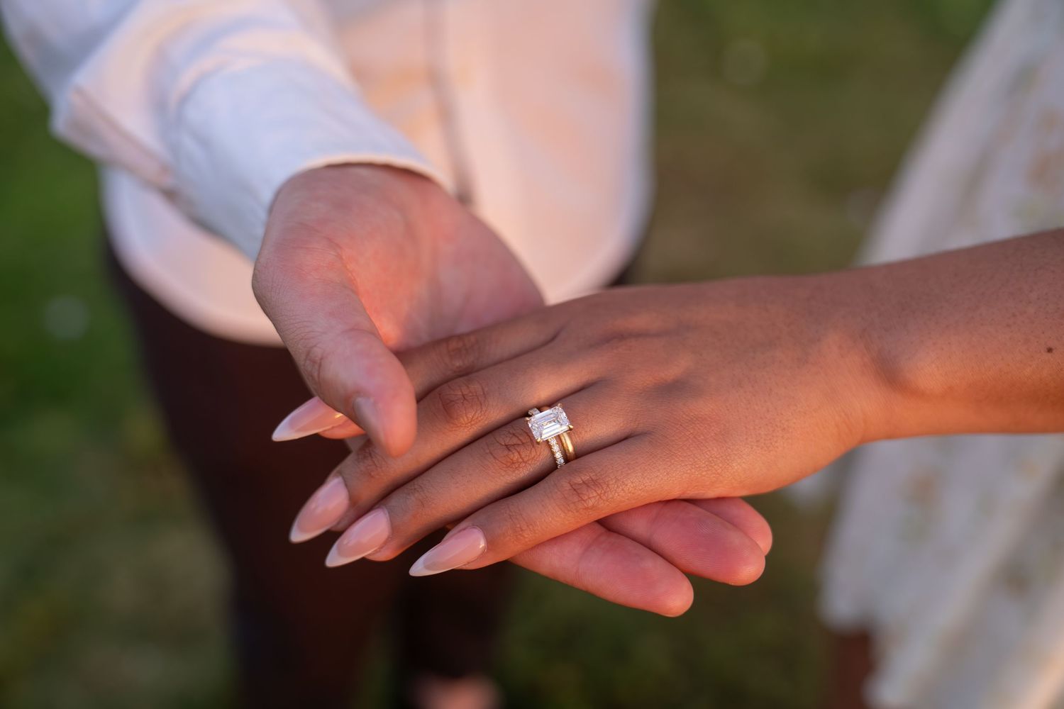 Close-up of hands displaying a sparkling diamond engagement ring with elegant long nails during a romantic proposal.