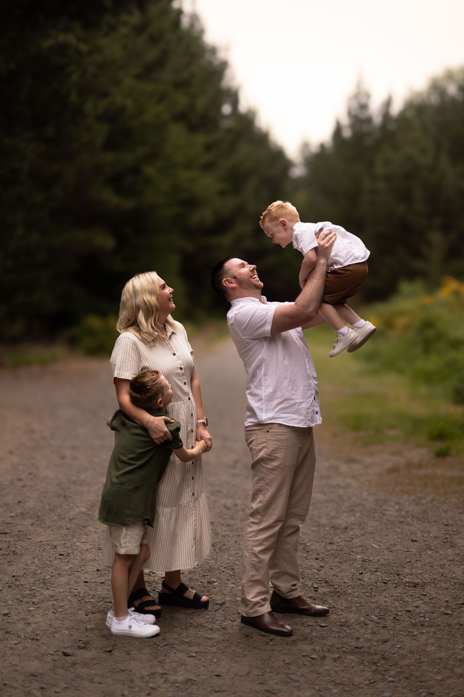 mum cuddling son and dad throwing son in the air during family session at bottle lake forest
