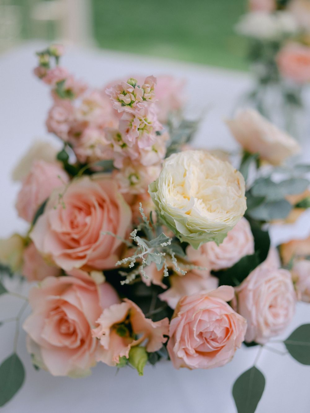 Elegant wedding centerpiece with blush pink roses and cream peonies arrangement.