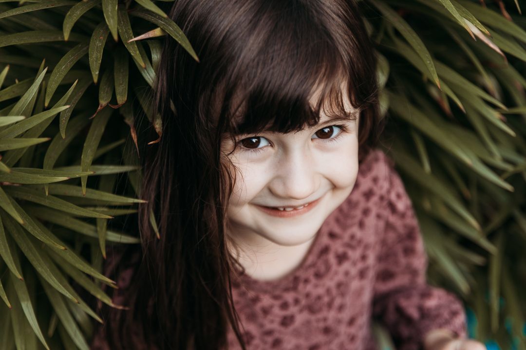 A sequence of candid expressions showing a child's changing emotions from thoughtful to joyful in a natural outdoor setting.