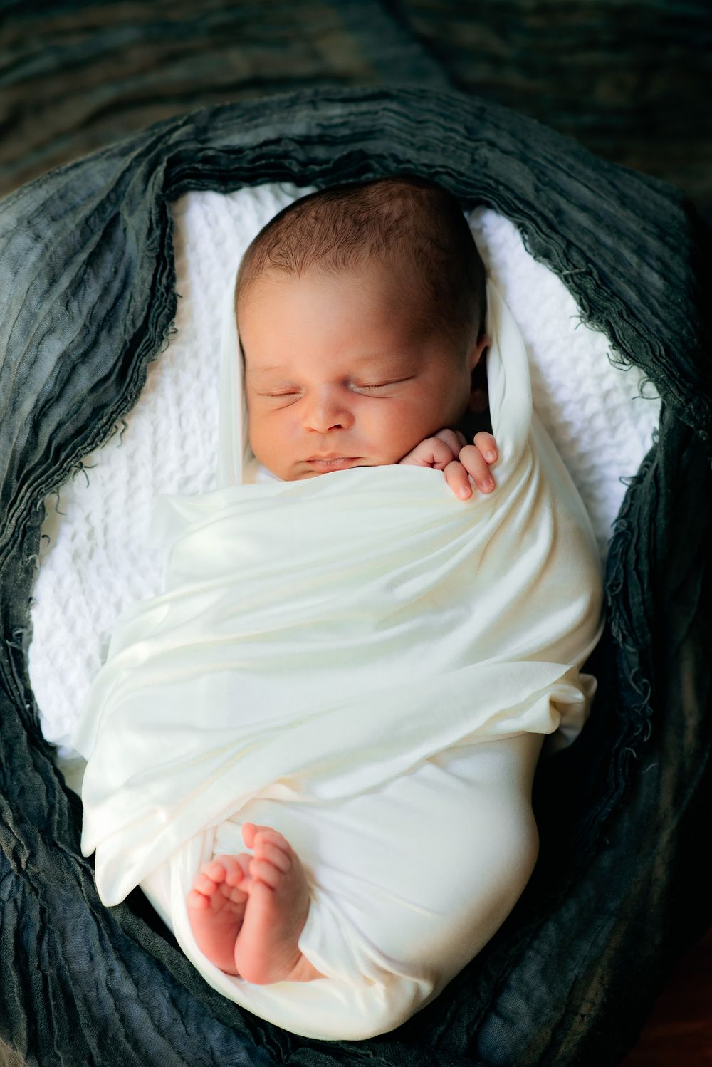 a newborn all snuggled up with his little feet sticking out of his wrap for his newborn session in Central Massachusetts