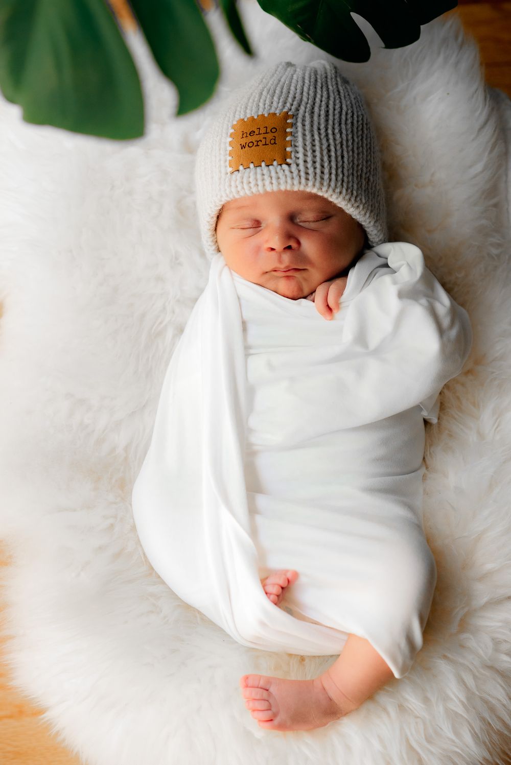 an adorable newborn all wrapped up laying on a furry rug during its newoorn in home photo session