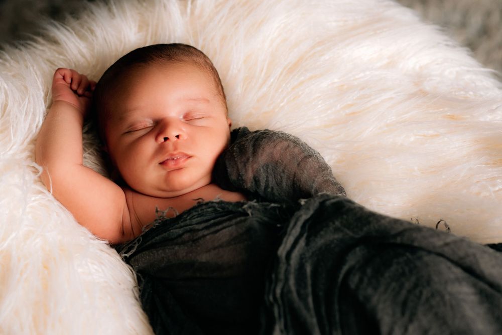 a newborn all snuggled up in beautiful light in their newborn photo session in Central Massachusetts