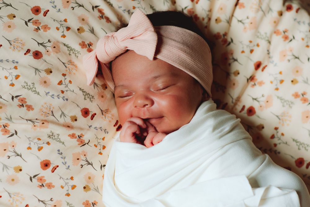 newborn baby girl sweetly smiling during in home newborn photography session in Worcester County