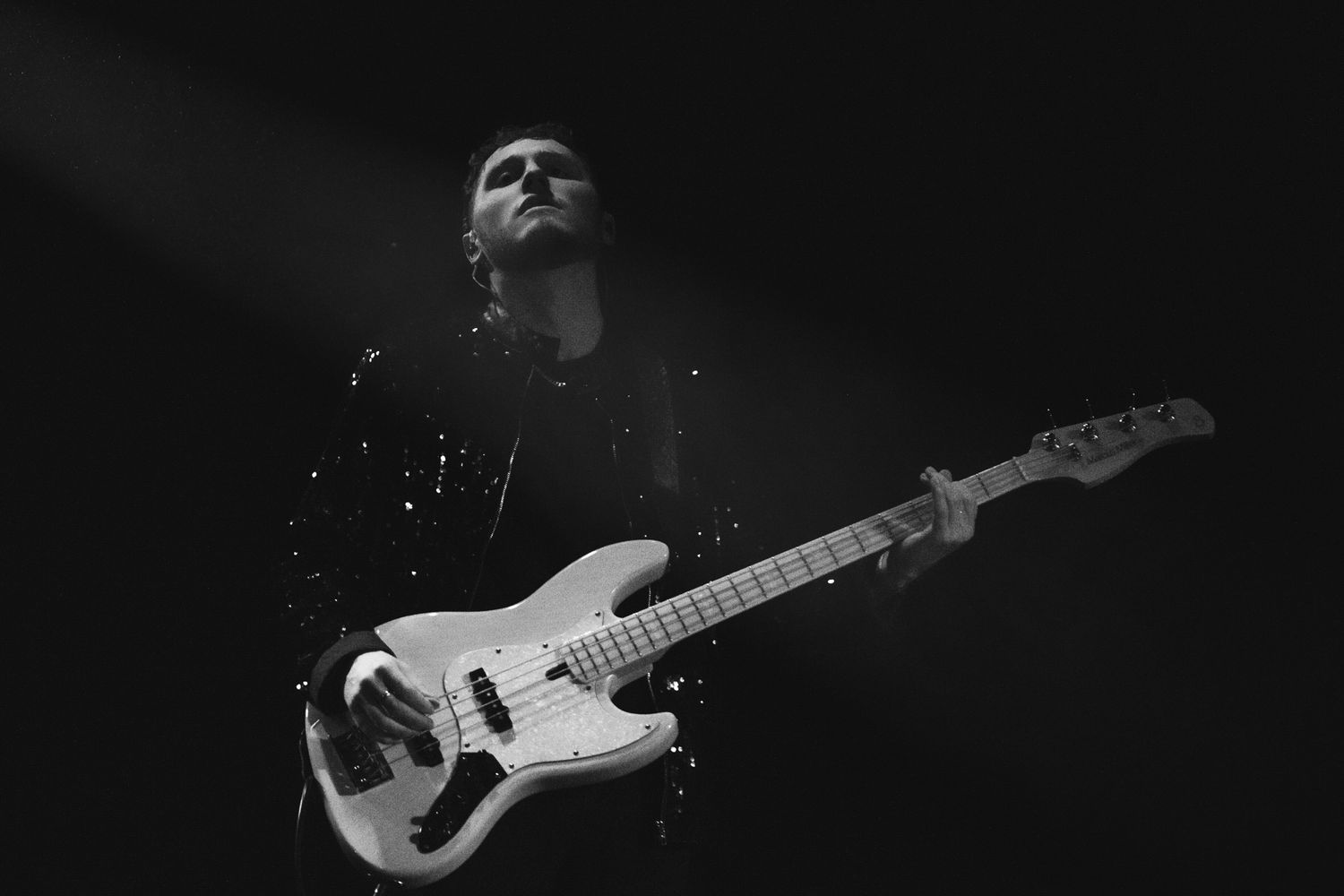 Black and white concert photo of guitarist performing on stage with dramatic lighting.