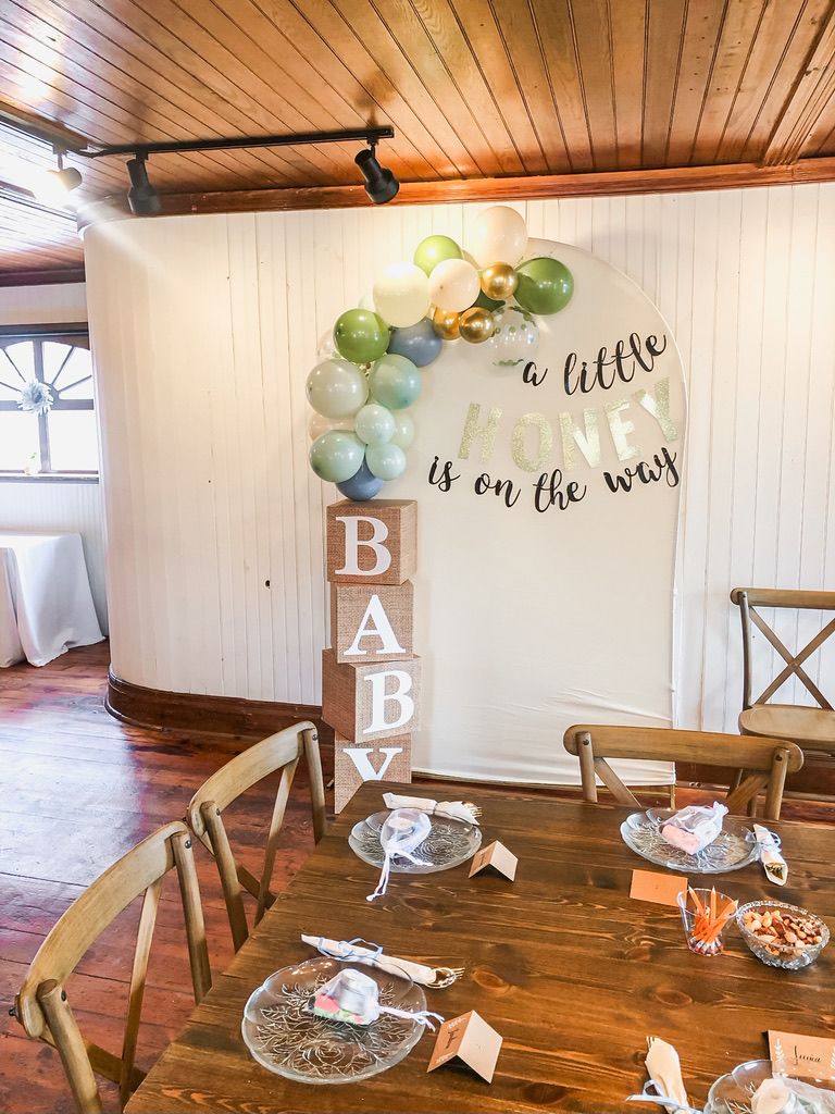 Baby shower decor with balloon arch, BABY letter blocks, and sign reading a little bunny is on the way.