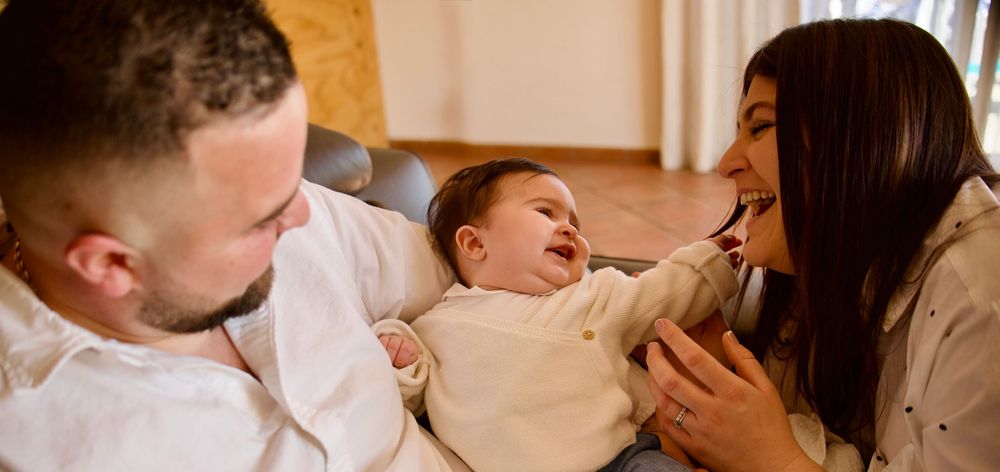 Parents jouant avec leur bébé lors d’un shooting famille à Meyreuil, scène de vie authentique en intérieur avec lumière naturelle