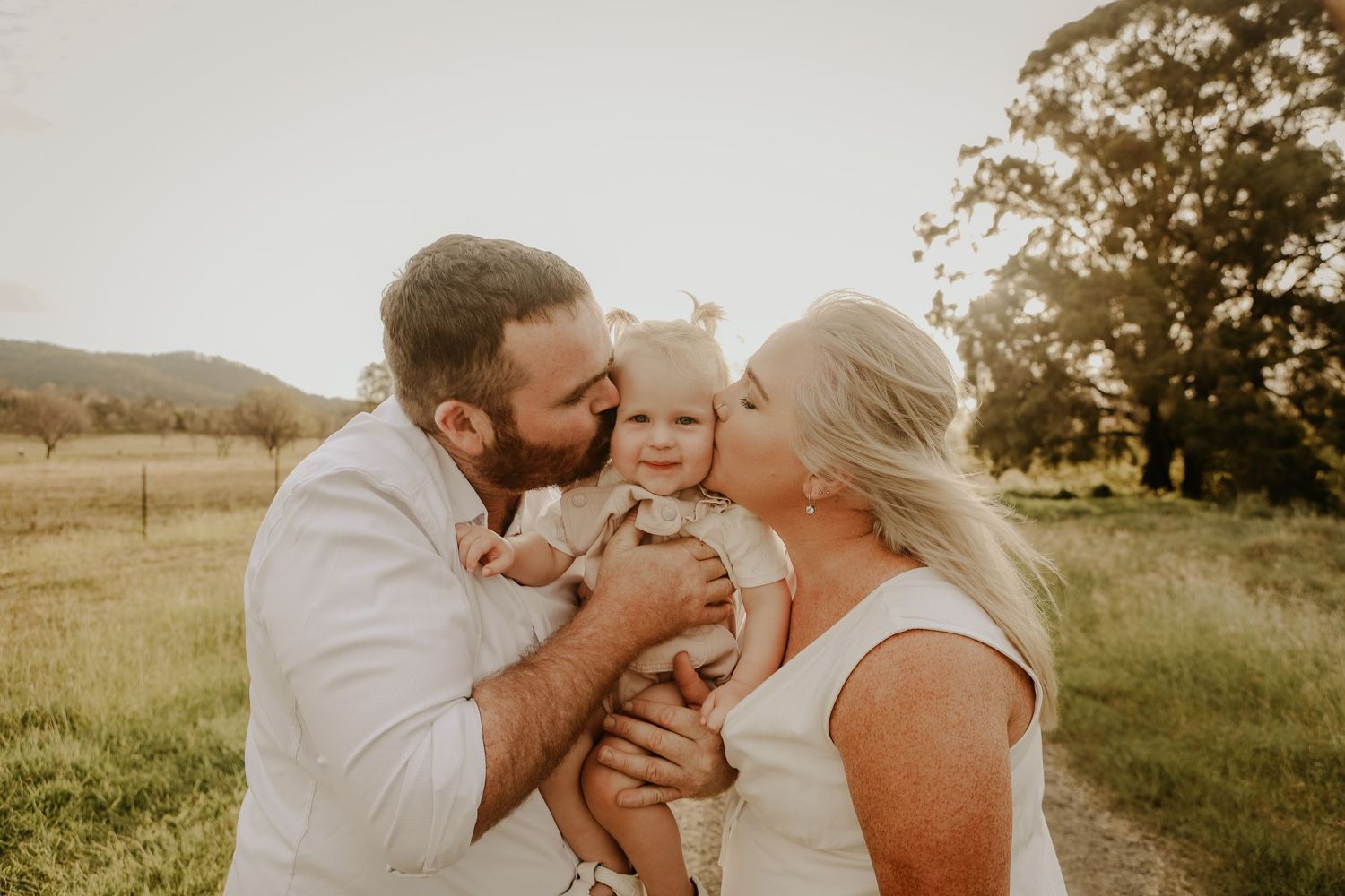 A loving family shares tender moments together in a sun-drenched field during golden hour.