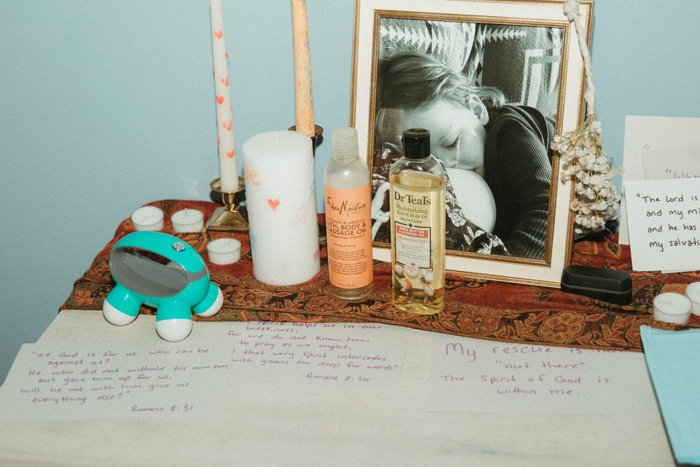 Home birth altar with candles, oils, framed photo, and handwritten affirmations on decorated table.