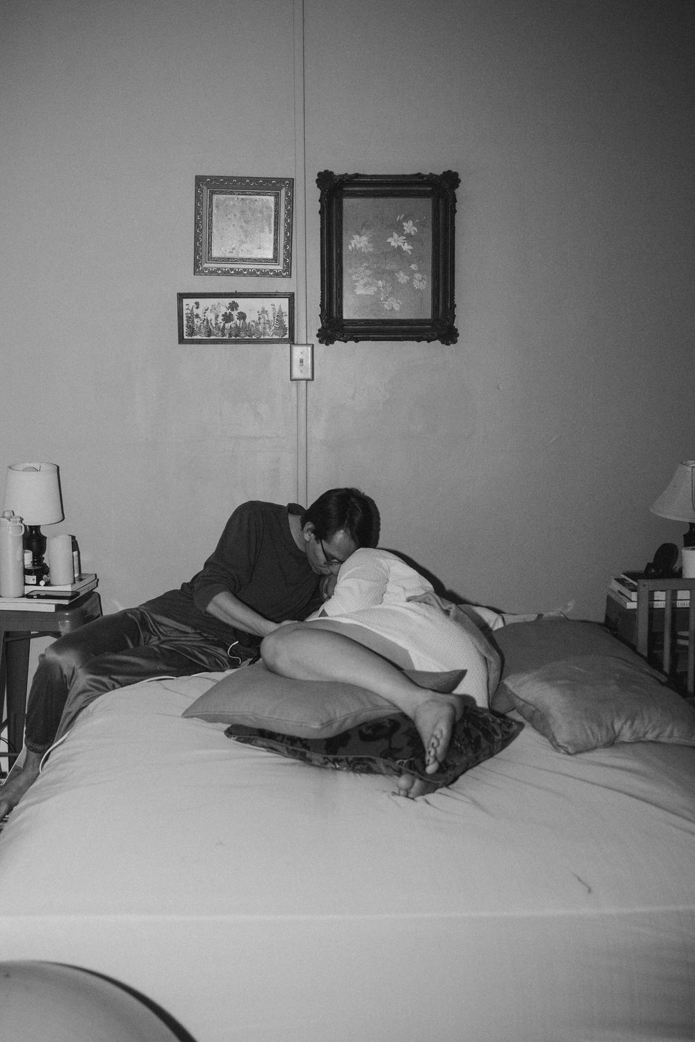 Black and white photo of couple sharing intimate moment on bed during home birth labor.