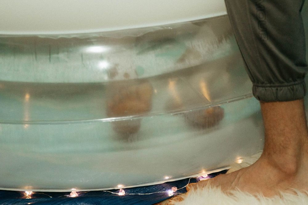 Close-up of an inflatable birth pool with LED lights along the base on a white carpet.