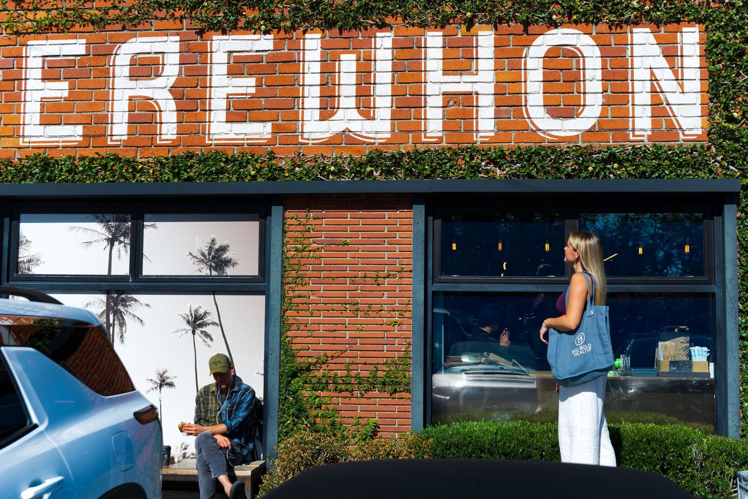 Exterior of Erewhon market with red brick wall and large white lettering signage above storefront windows.