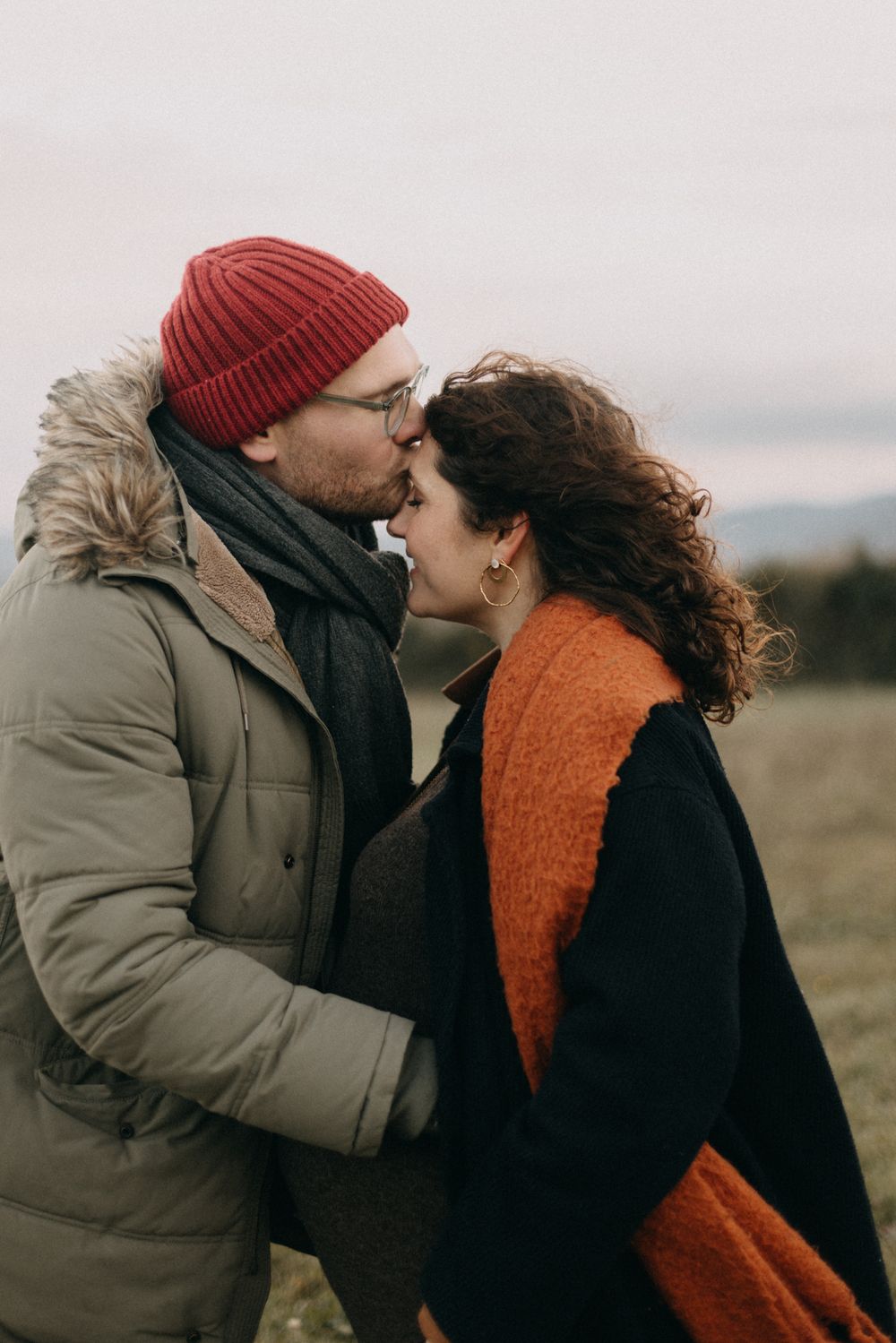 A couple in winter attire sharing tender moments in a series of four romantic photos in a natural outdoor setting.