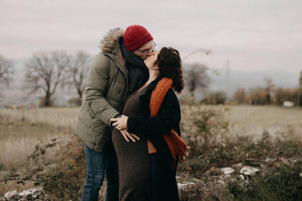 A couple embraces in a misty field during autumn while wearing cozy sweaters and jackets.