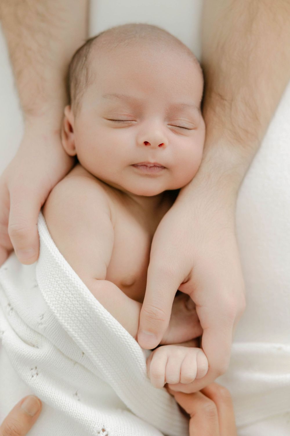 Peaceful sleeping newborn wrapped in white blanket against neutral background in the Connecticut Studio.