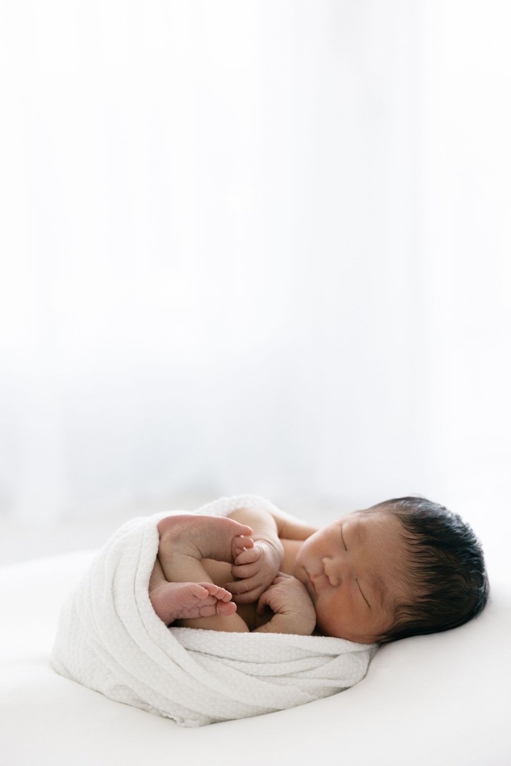 Sleeping newborn peacefully resting on white surface in natural light in the Connecticut Studio.