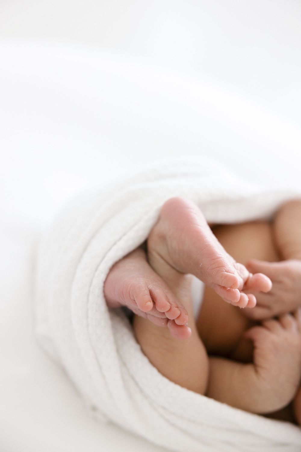 Close-up of tiny baby feet peeking out from soft white blanket in the Connecticut Studio