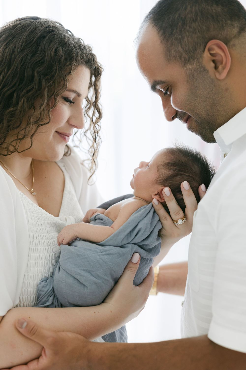 Tender family moment captured in soft white studio lighting with newborn baby in the Connecticut Studio.