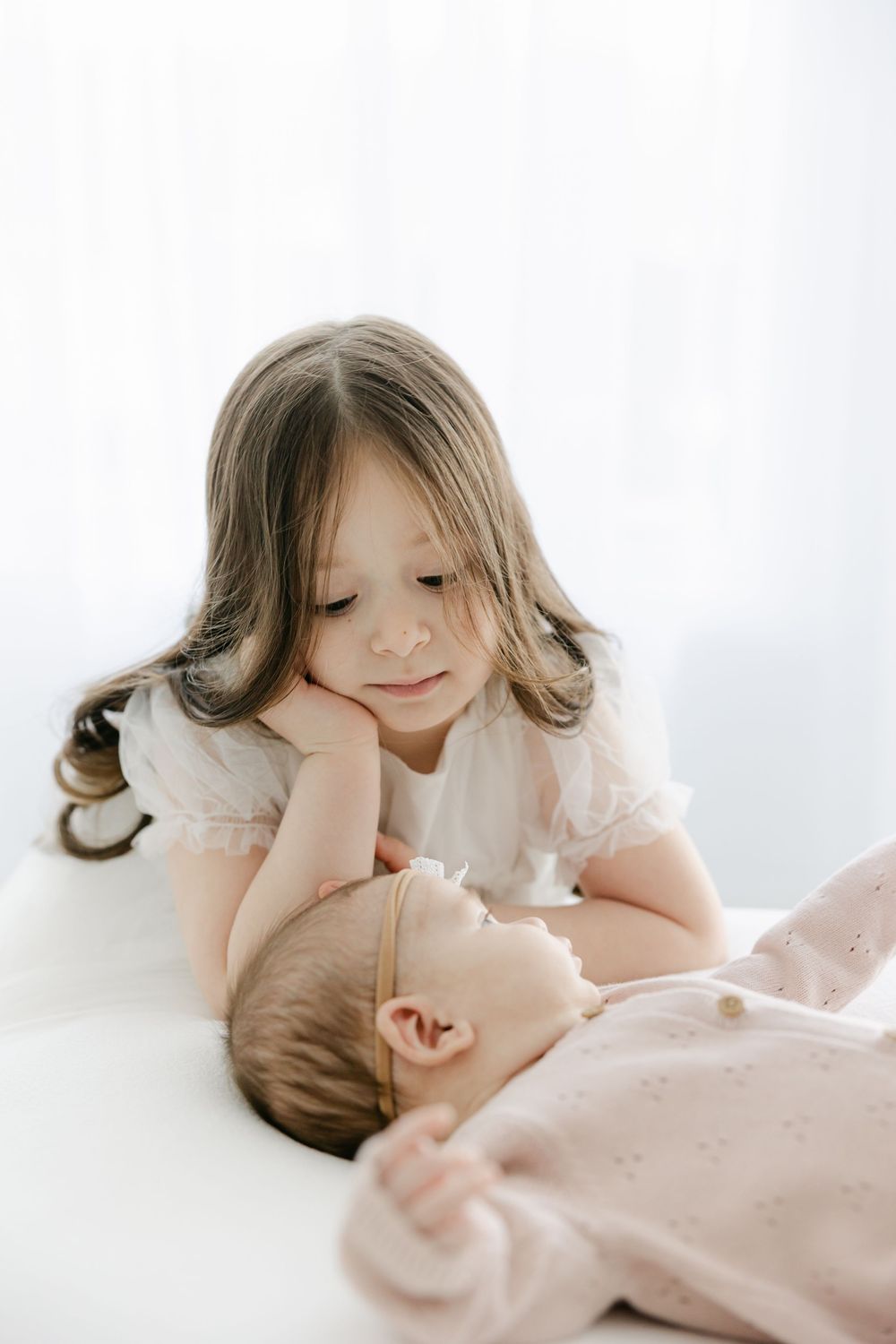 Gentle interaction between siblings captured in soft, dreamy studio lighting in the Connecticut Studio.