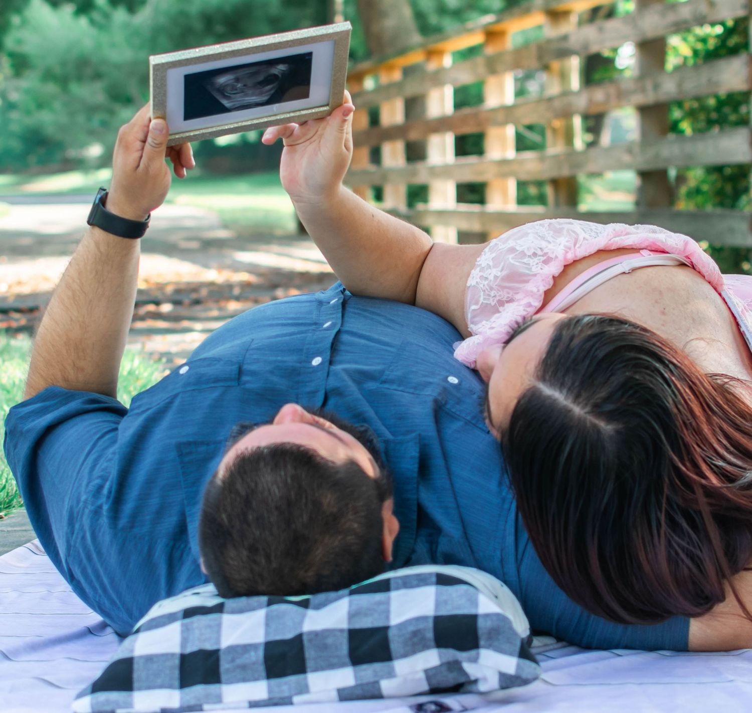 A person lies on a wooden deck outdoors while looking at their mobile phone in a relaxed position.