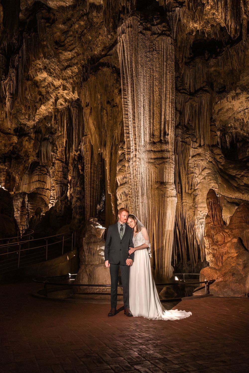 A romantic wedding ceremony takes place inside a dramatic cave with illuminated stalactites and stalagmites.